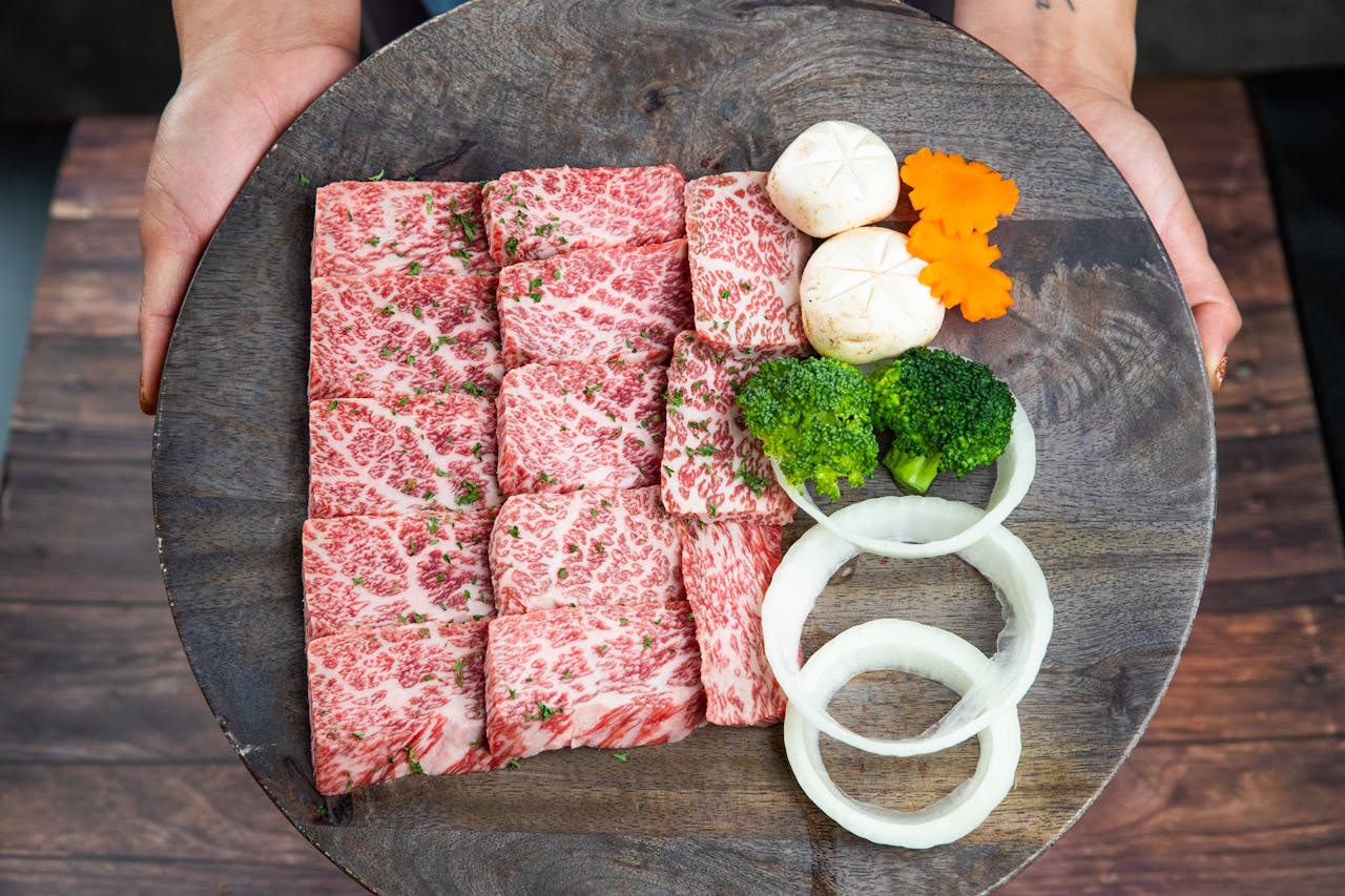 Wagyu beef with broccoli, onion, and mushrooms on a rustic plate, held by hands.