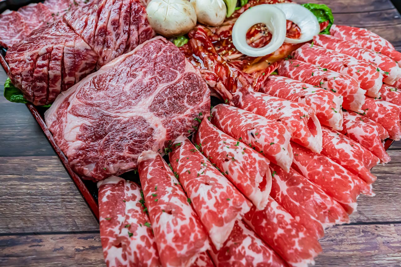 Close-up of marbled raw wagyu beef slices on a wooden tray, ideal for cooking.