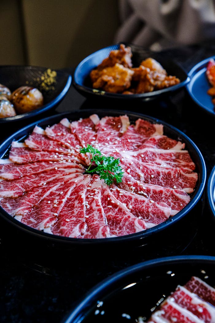 Elegant presentation of thinly sliced Wagyu beef with side dishes, perfect for a gourmet dining experience.