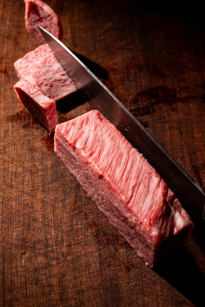High-quality A5 Wagyu beef being sliced on a wooden cutting board in Orlando, Florida.