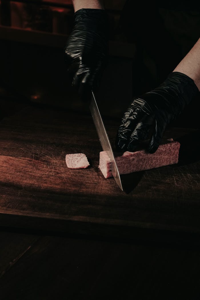 A chef slices fresh wagyu beef with precision on a wooden board, showcasing culinary excellence.