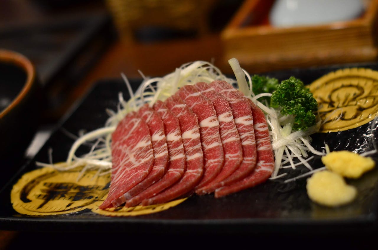 Thinly sliced Wagyu beef sashimi with garnish served in a traditional Japanese style.